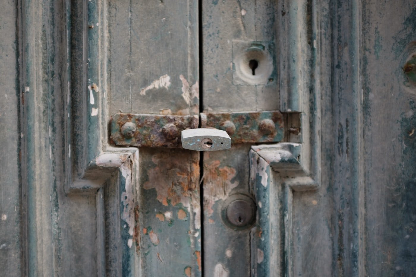 Padlock and latch on a weathered timber door
